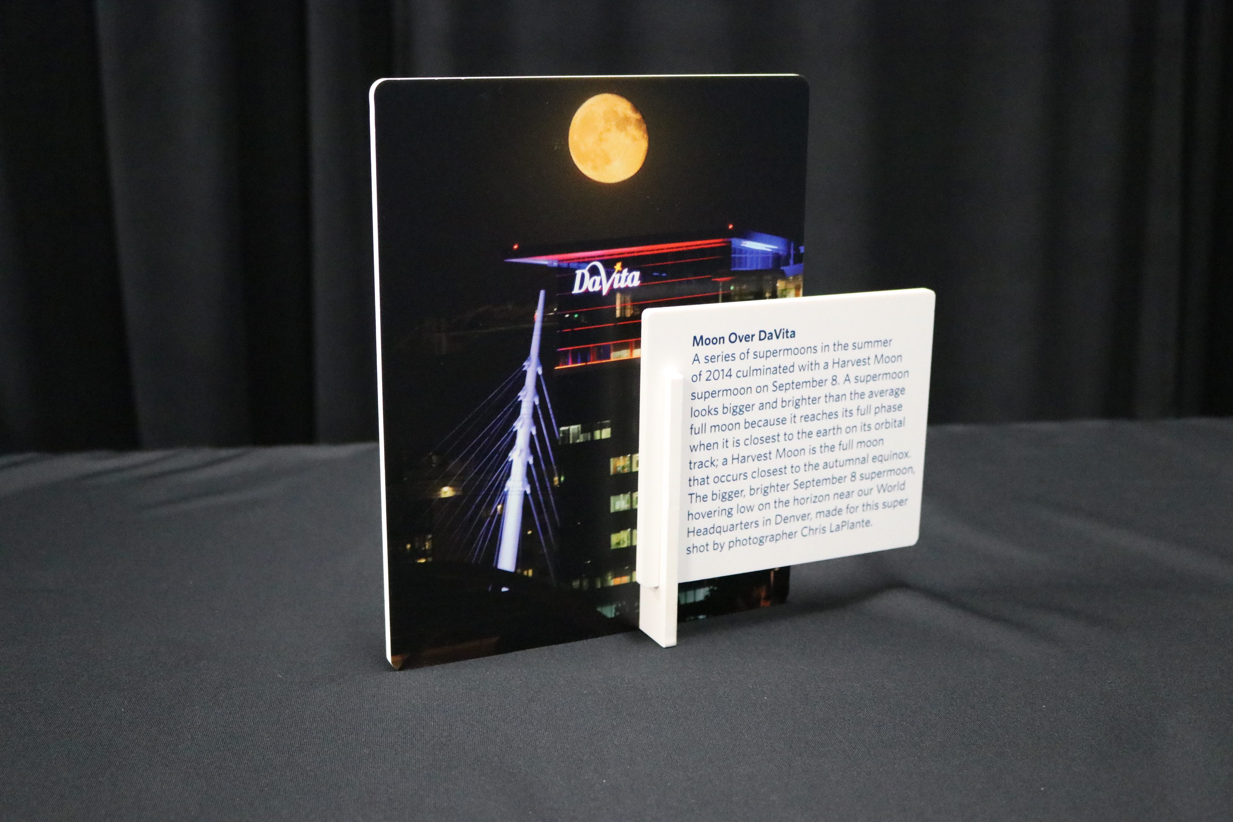 Tabletop display of a picture of a moon over a building with a description of the picture infront.
