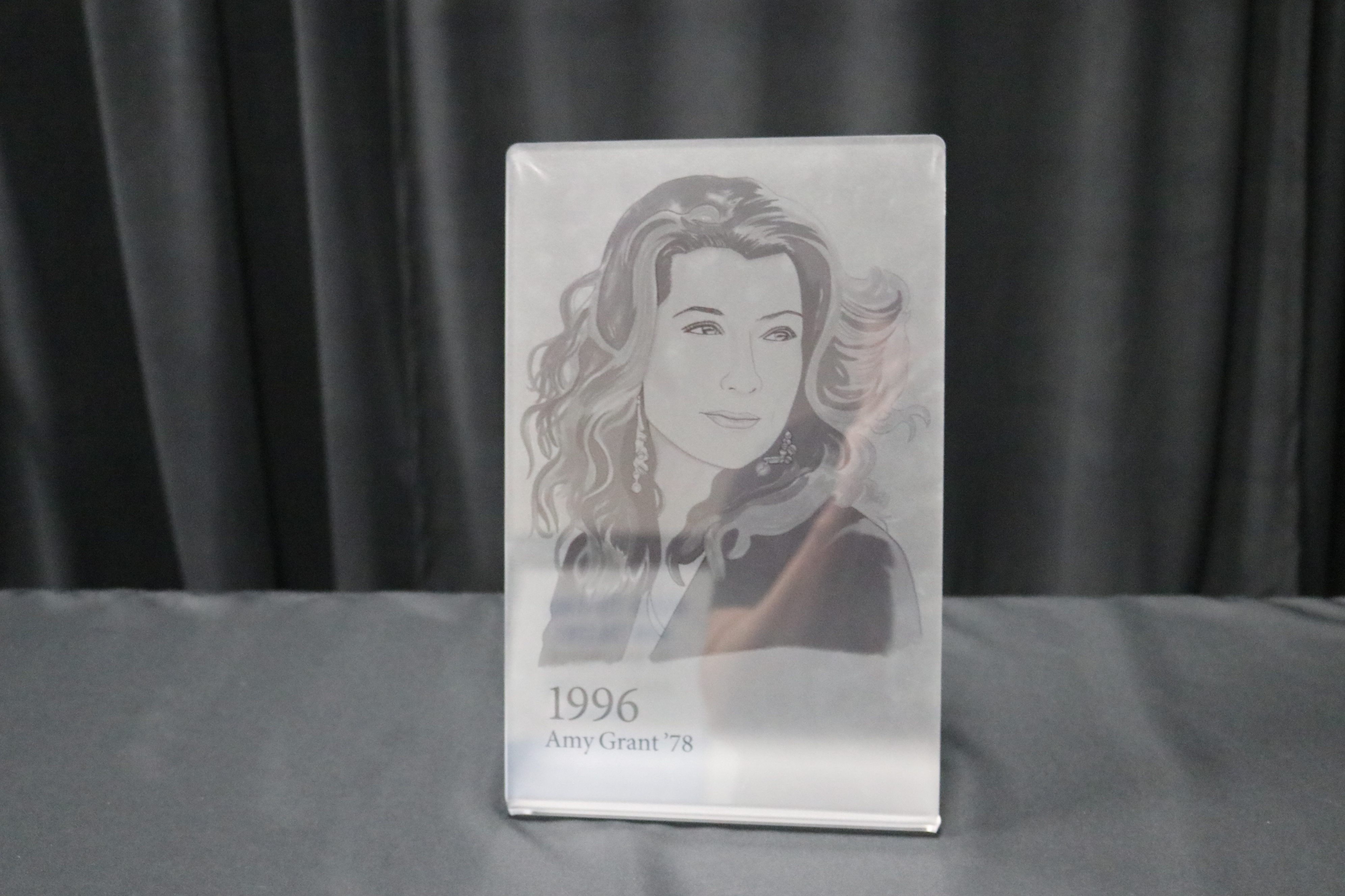 Frosted acrylic tabletop display bent at base with picture of Amy Grant directly printed on frosted side.