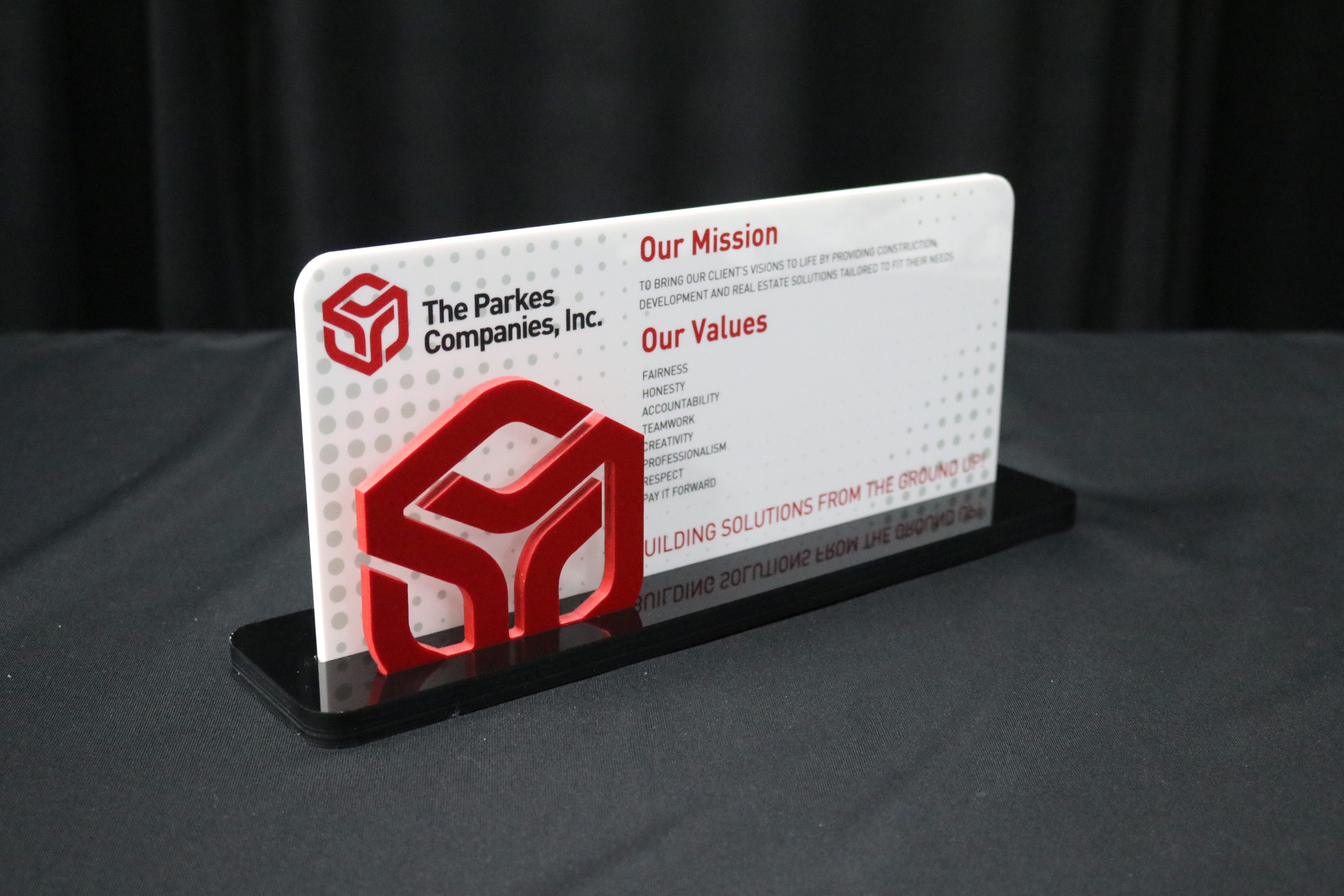 Conference room table top display with mission and core values printed on white acrylic, logo cut out of red pvc, inserted into black acrylic base.