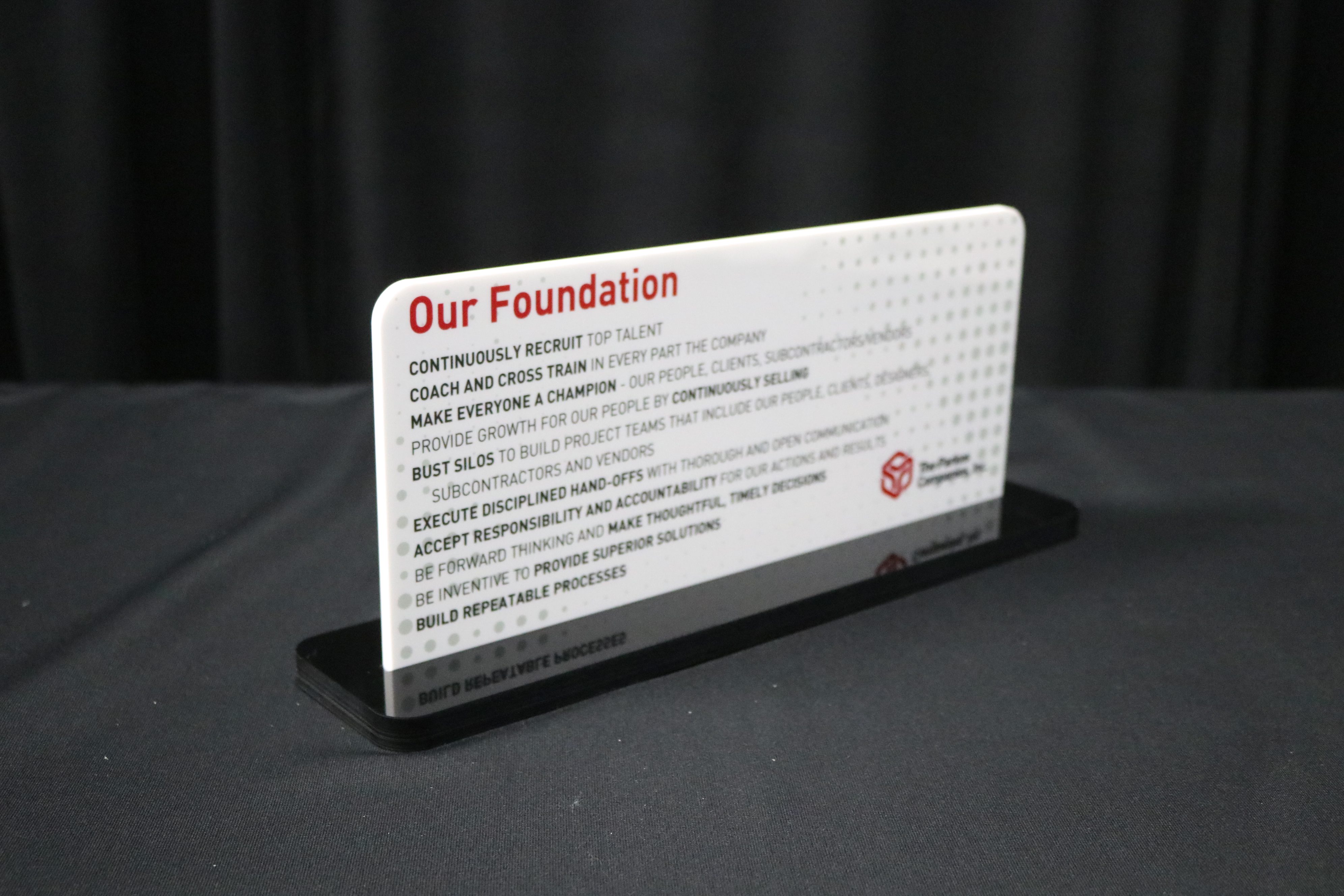 Printing of company values on white acrylic in a black acrylic base