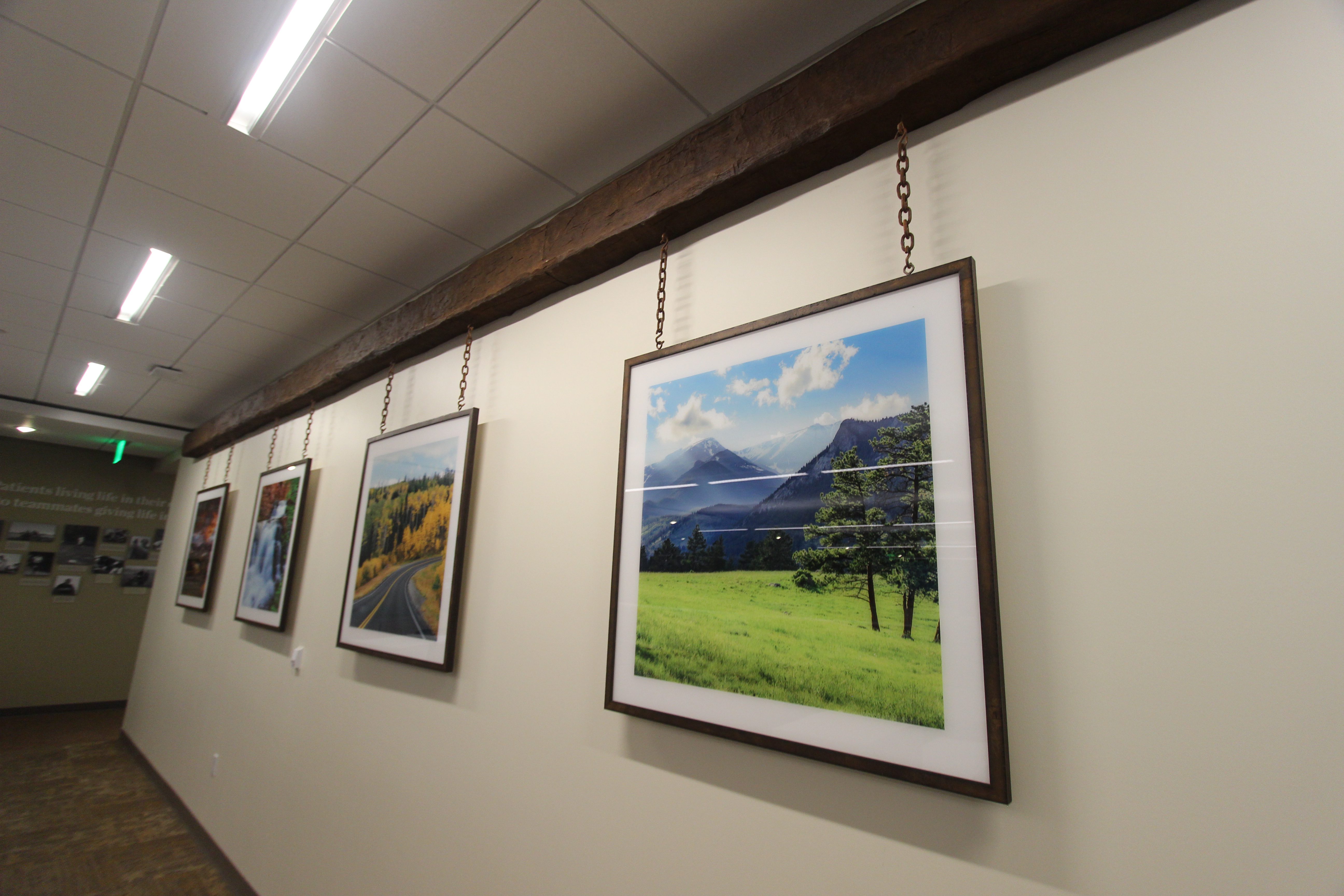 Acrylic images framed hung by chain from a faux wood beam in corporate office.