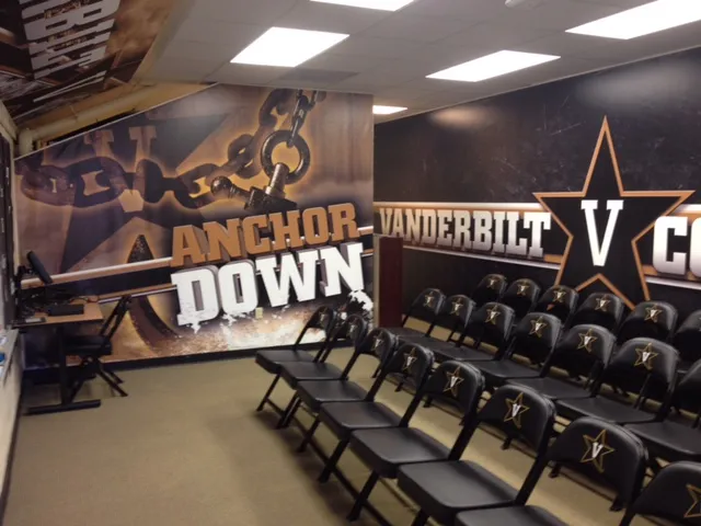 An athletic locker room featuring school branding on all walls, using vinyl banners as changeable wall coverings to create a dynamic and spirited atmosphere.